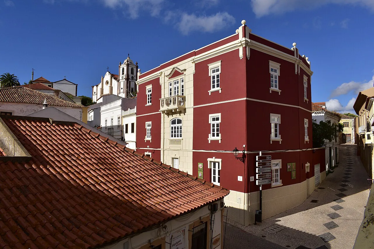 A red-painted town house in Silves, with the cathedral tower in the background.