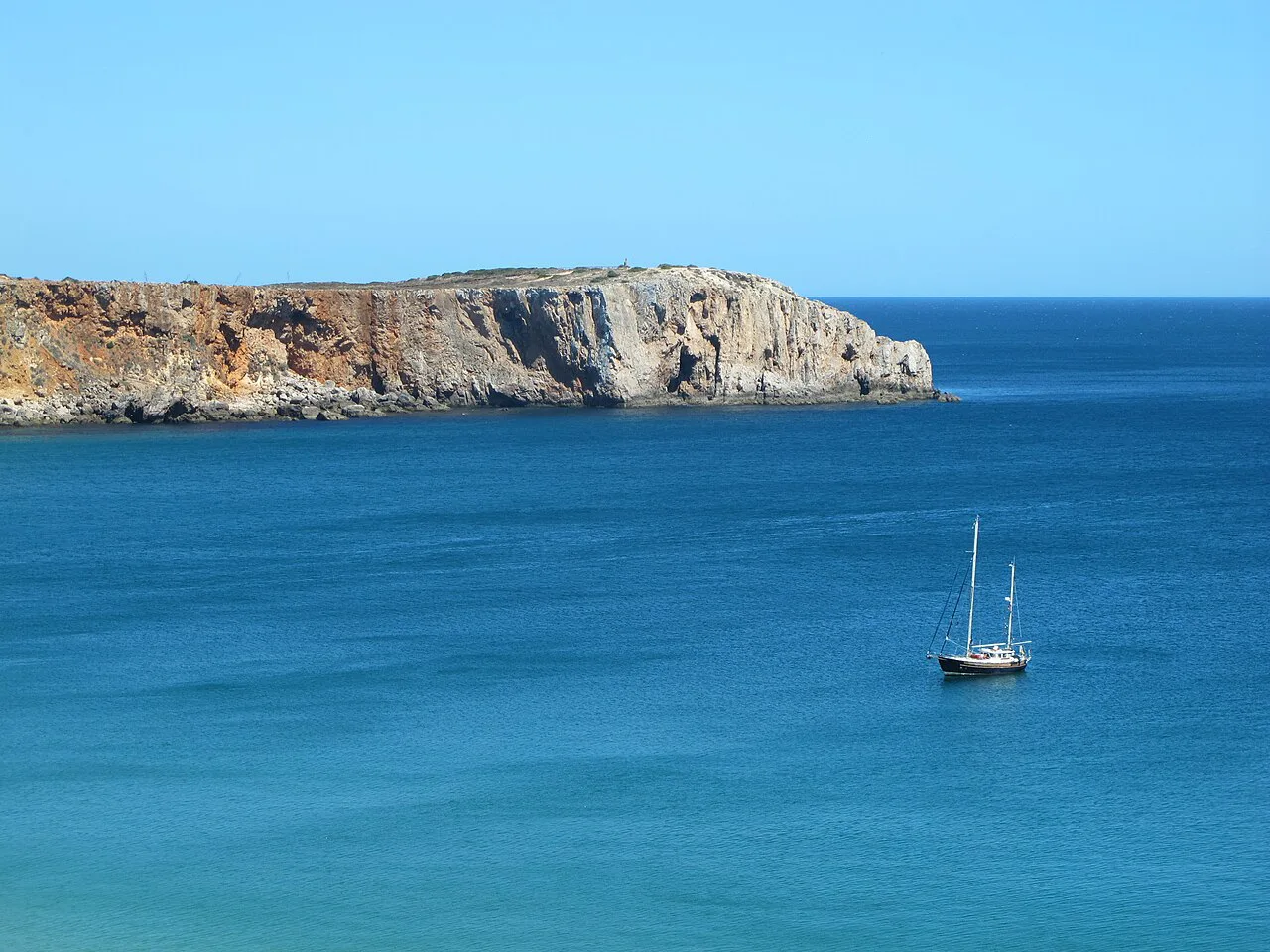 A sailing boat anchored off the cliffs at Sagres.