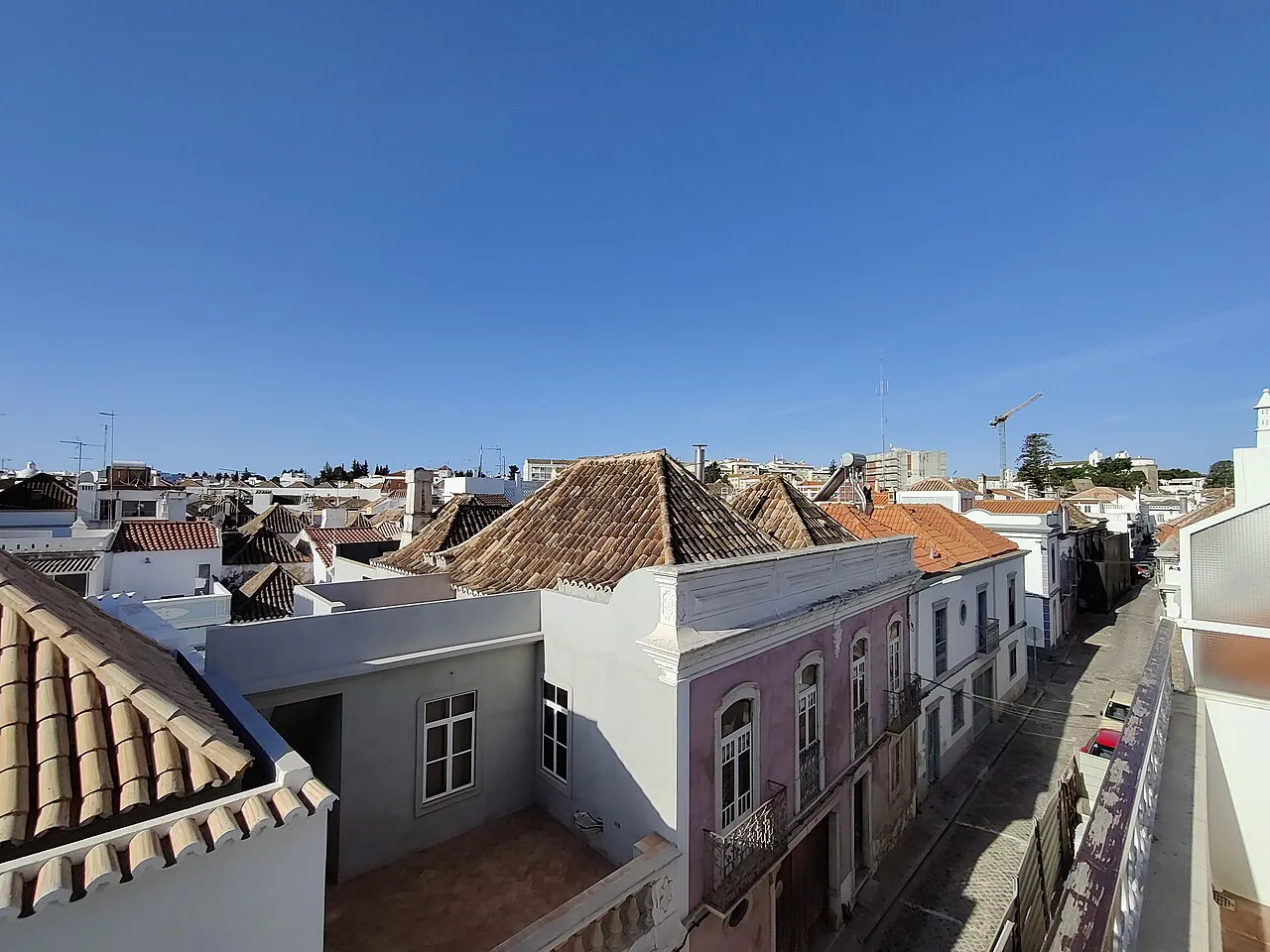 Tiled rooftops and whitewashed houses along a street in Tavira.