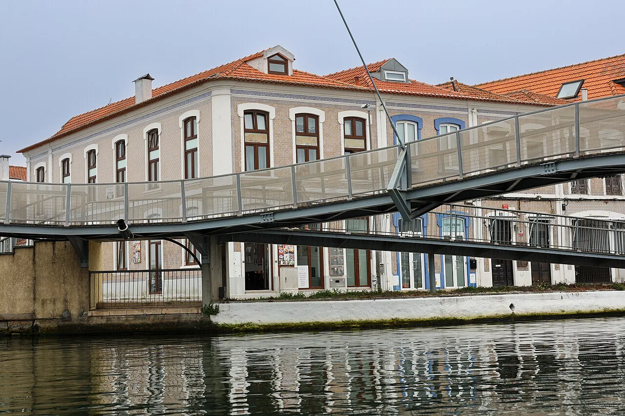 A footbridge over a canal in front of a historic building in Aveiro.