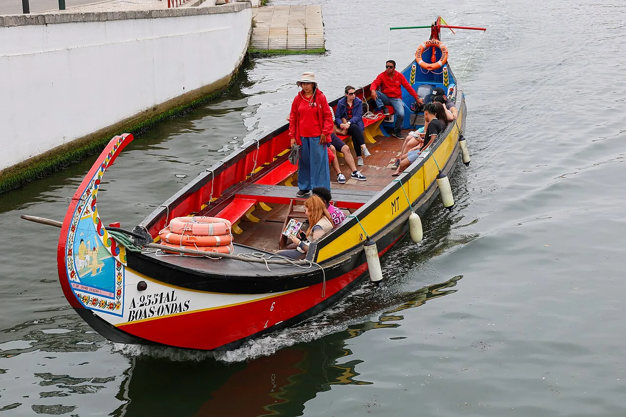 A painted moliceiro boat carrying passengers along a canal in Aveiro.